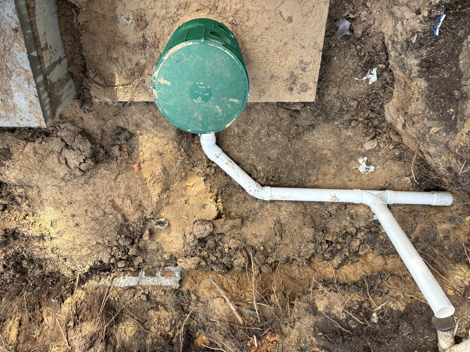 Newly installed green septic tank lid and white PVC drain line set in a residential yard