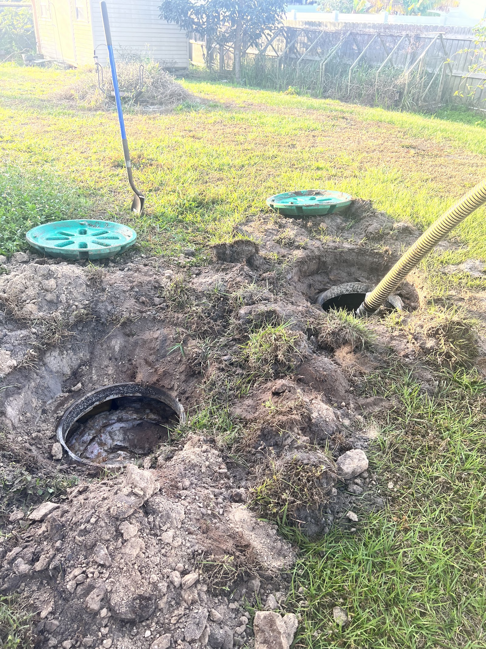 Excavated septic system with exposed concrete tank and access lids during a home inspection