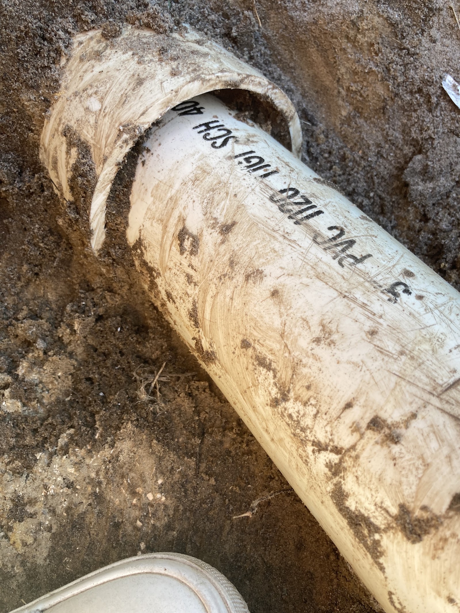 Freshly cut white PVC septic line ready to be installed on a repair call