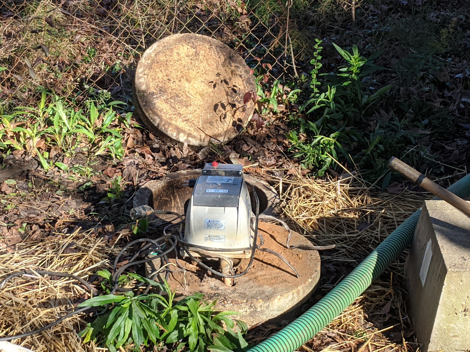 J&J Septic crew inspecting a septic tank lid with diagnostic equipment