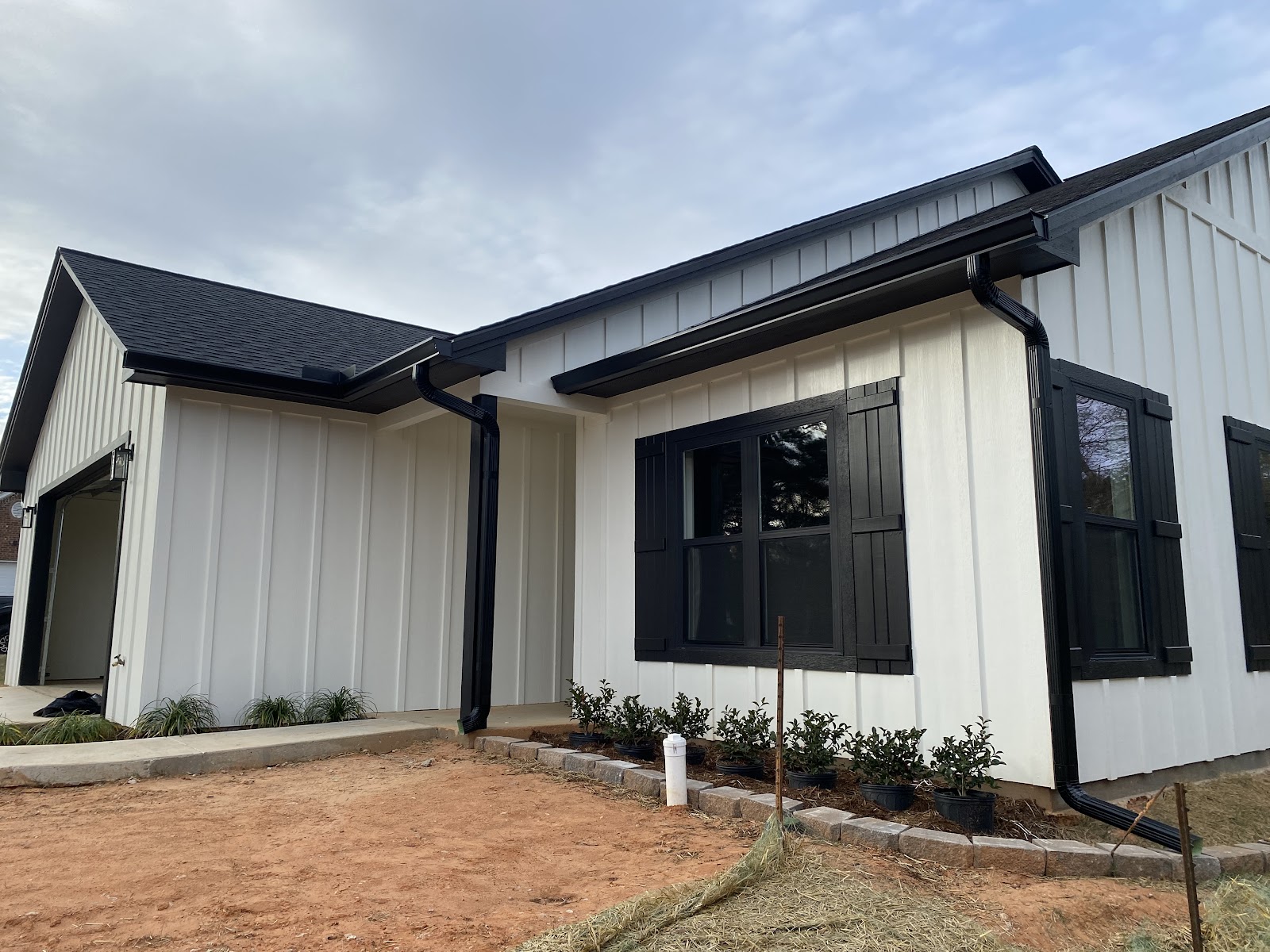White board-and-batten home with clean black gutters and downspouts in Nacogdoches, TX