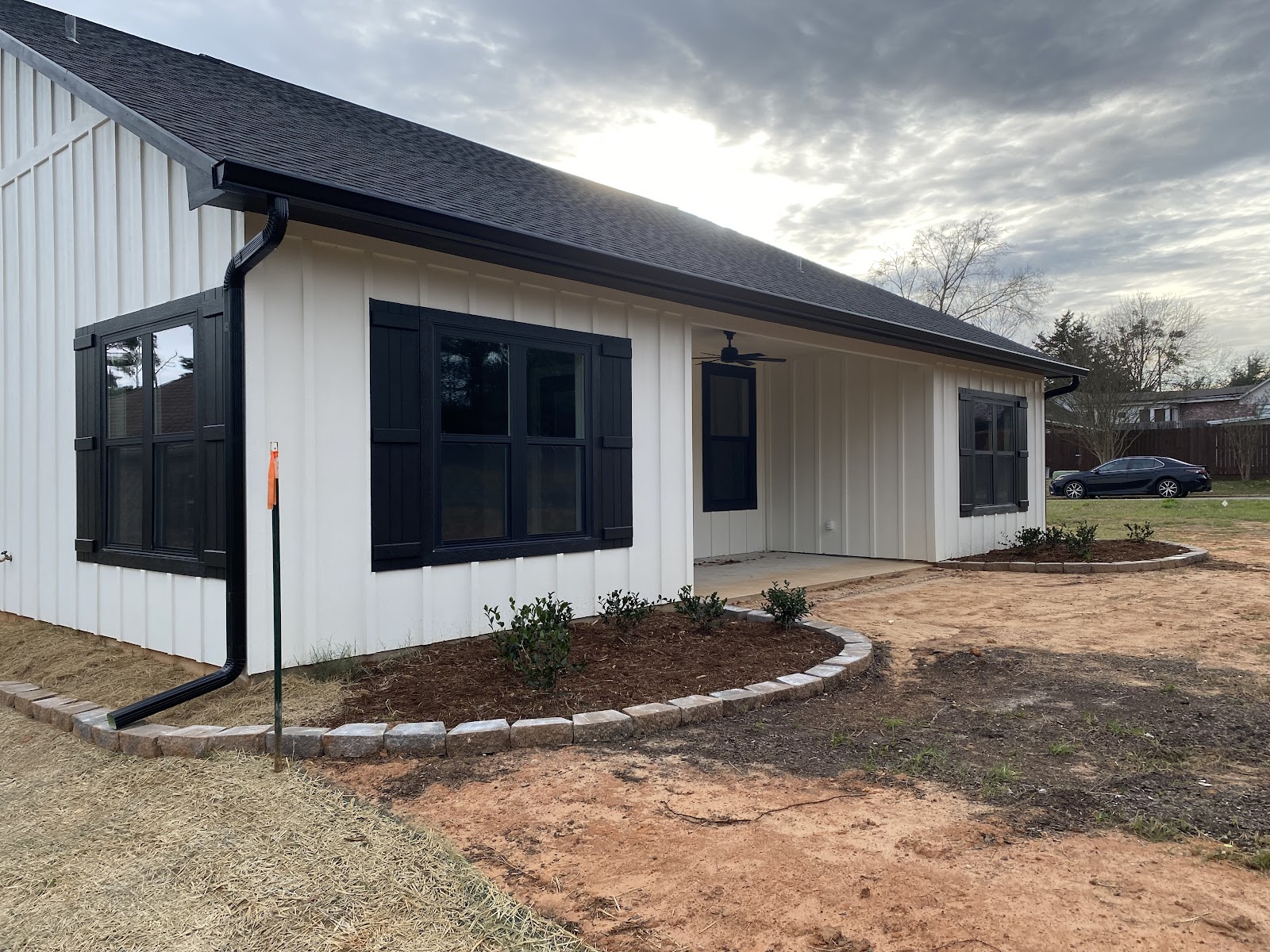 White farmhouse-style home with black gutters and downspout after gutter repair in East Texas