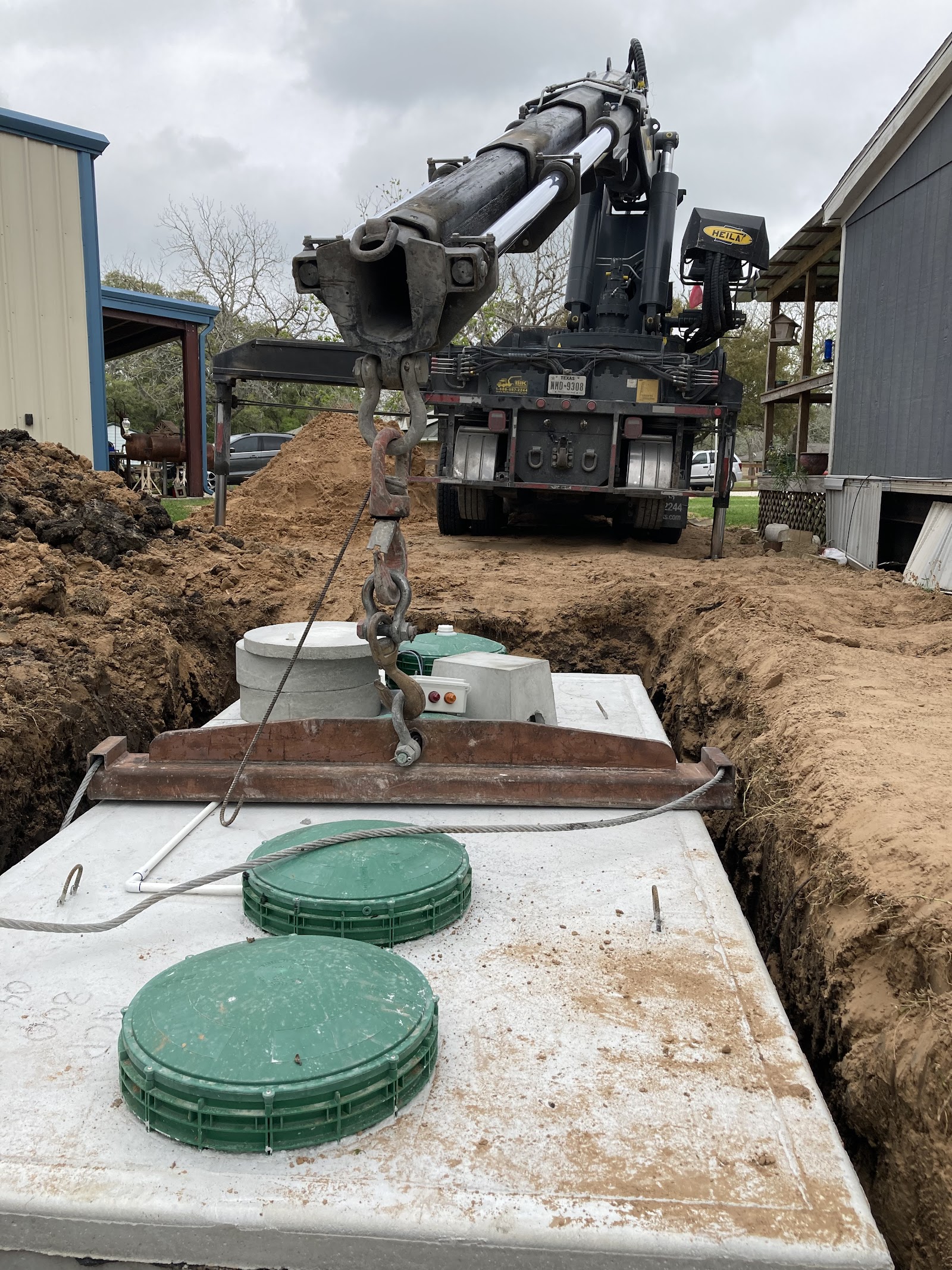 Septic tank system installation with pump truck and green access lids in residential yard.