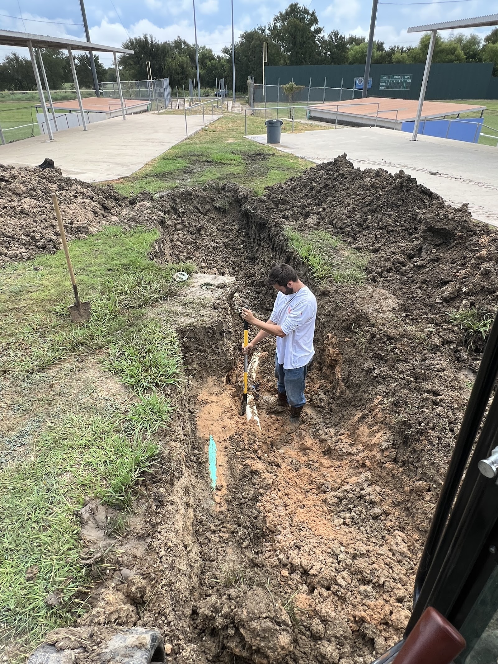 7H Septic technician inspecting deep excavated trench with measuring tools
