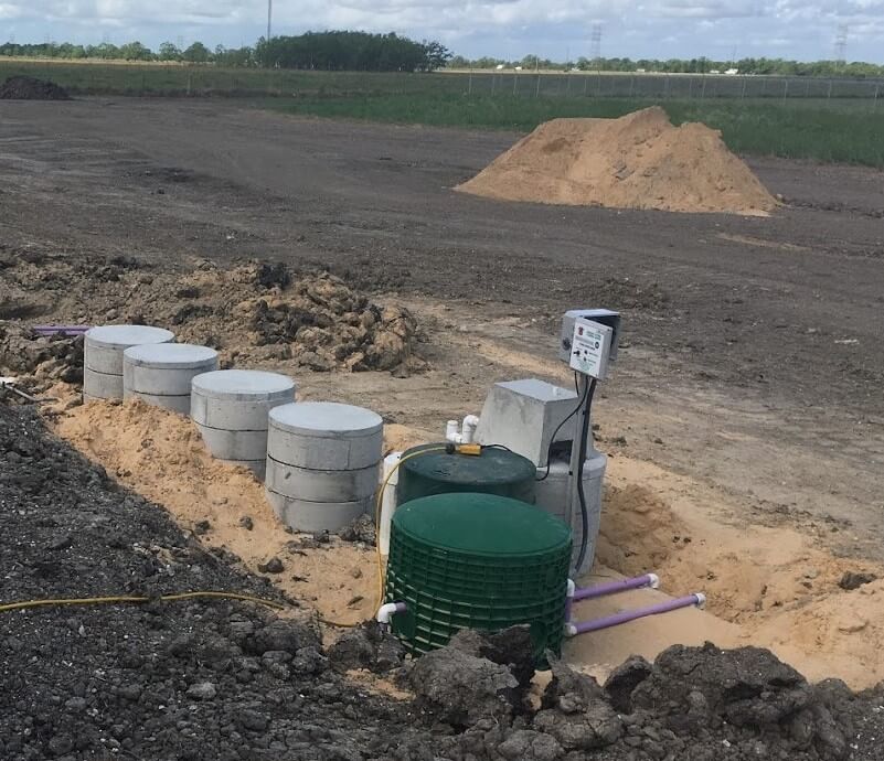 Septic tank system installation with concrete tanks and green holding tank at jobsite