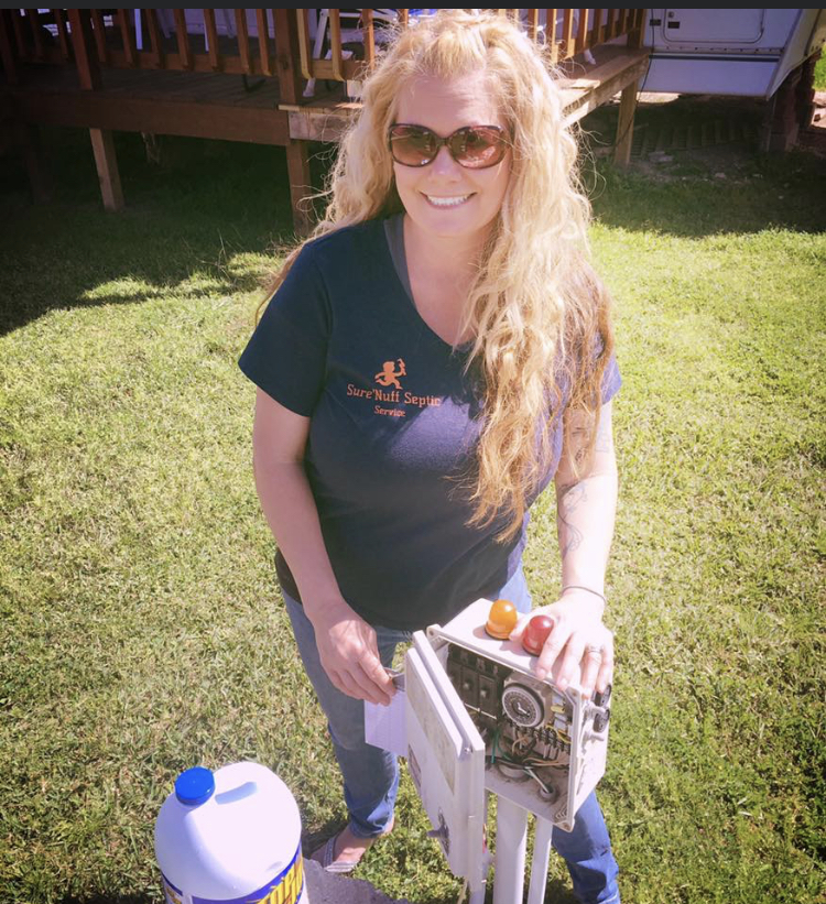 Sure'Nuff Septic team member in branded t-shirt presenting septic system equipment in a residential yard.