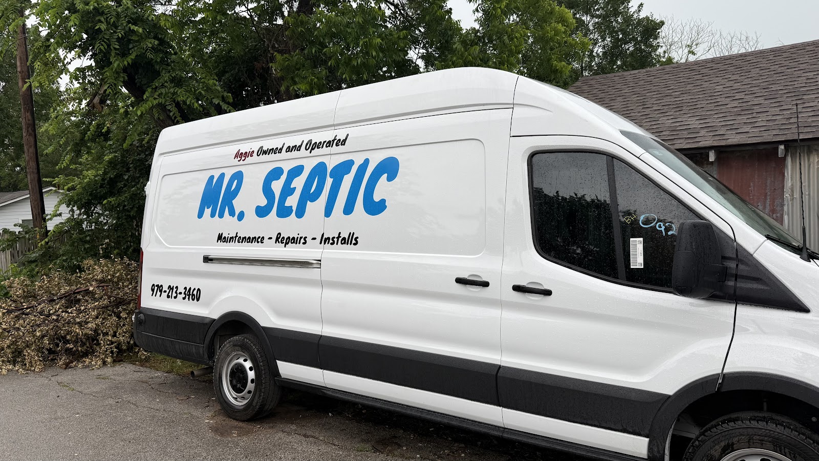 Mr. Septic white high-roof septic service van parked beside a tree and a house