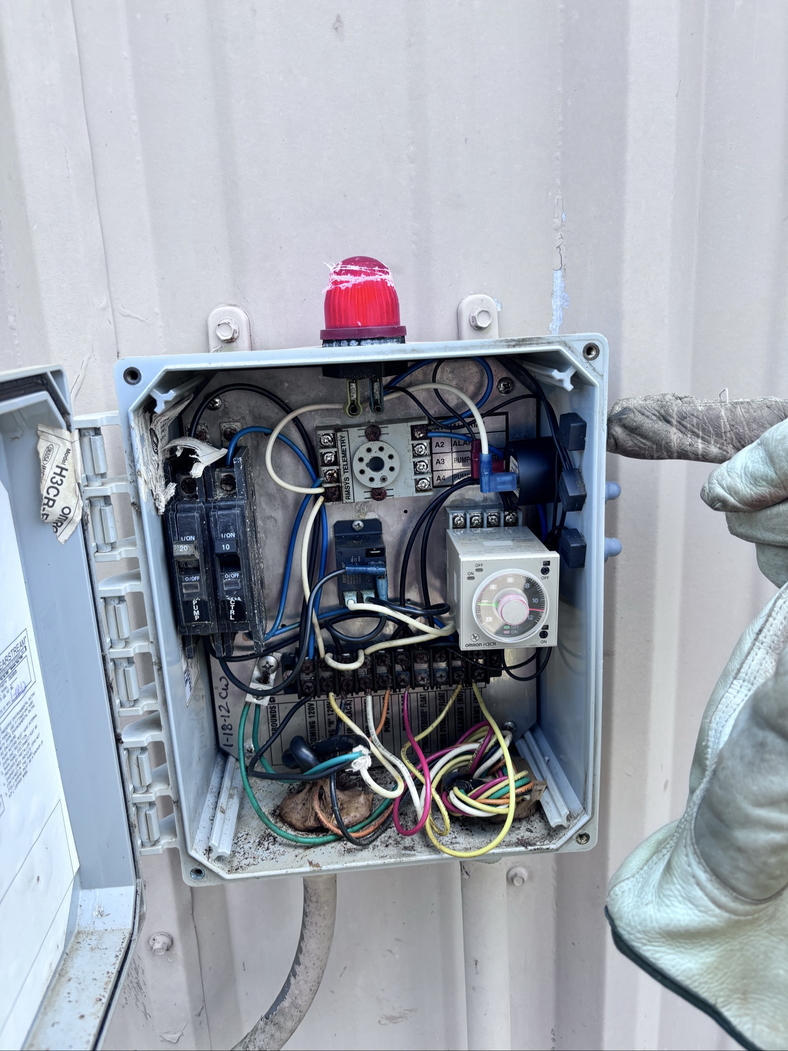 Electrical control panel box mounted on exterior wall with wiring and components visible